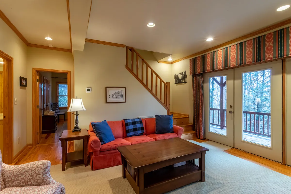 A vibrant living space with a red sofa, wooden coffee table, and large windows that offer glimpses of the natural surroundings. The view out the windows hints at the proximity to nature, while the cozy interior is perfect for warming up after time spent outdoors.
