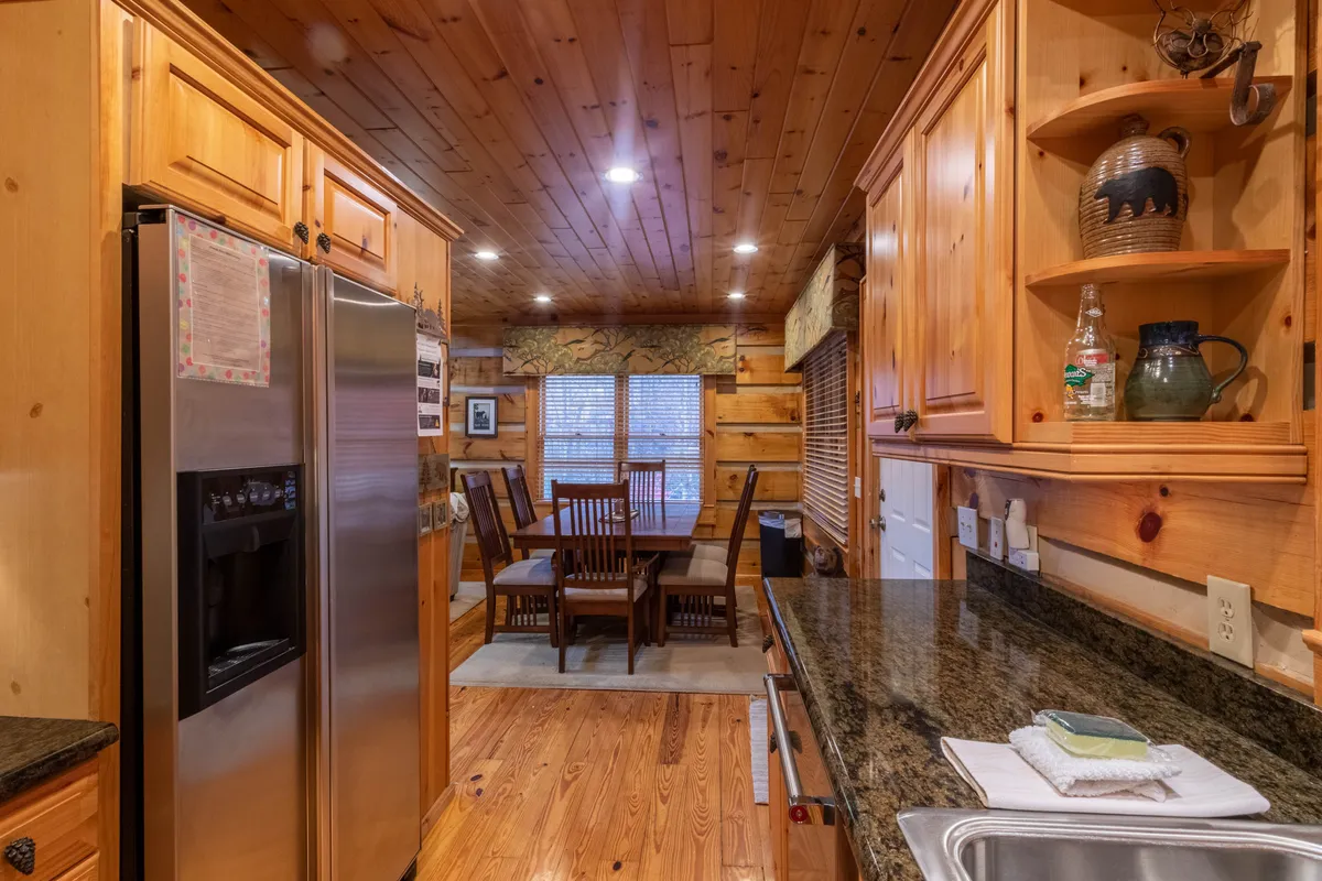 The photo centers on a kitchen island and dining table surrounded by warm wooden cabinetry. The open layout makes it easy for the chef to be part of the action, whether preparing food or joining conversations with guests nearby. The welcoming mood is highlighted by signs of both family meals and intimate gatherings.