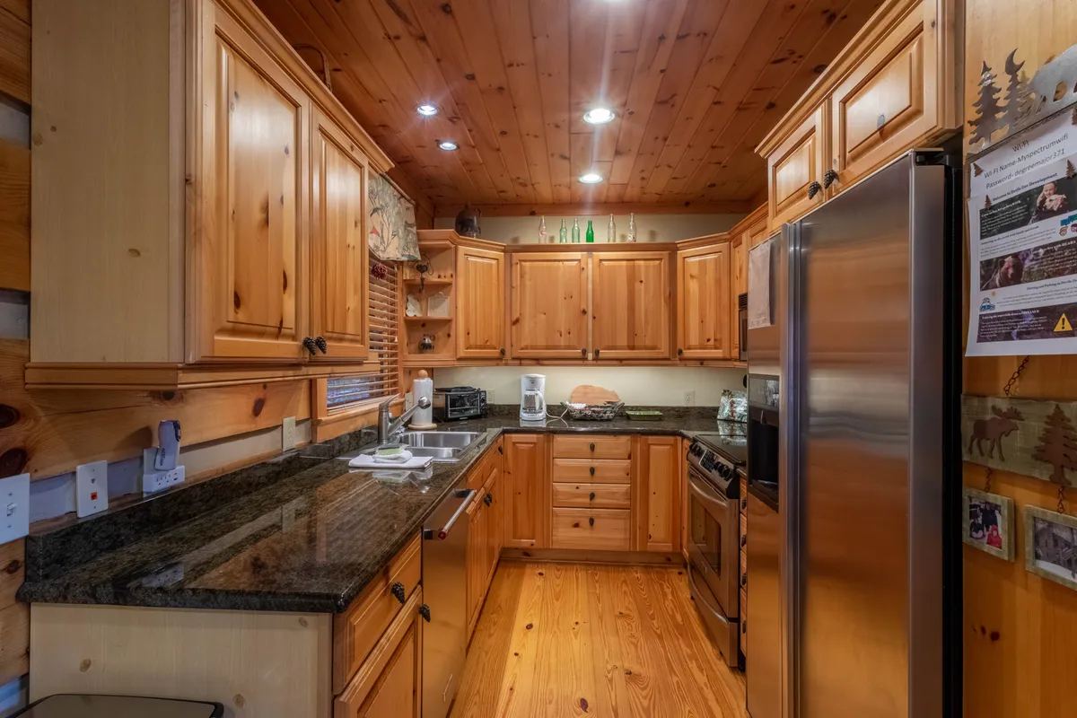 This interior shot highlights the kitchen's granite countertop, wooden cabinetry, and stainless steel appliances. The setup is warm and rustic, with plenty of space for meal preparation. The appliances gleam and the layout is clearly designed for both everyday cooking and hosting gatherings, reflecting the kitchen as a central, social space.