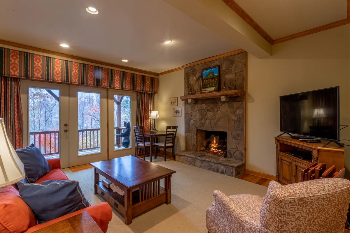 A welcoming family room with a stone fireplace, comfortable sofa, and dining table, all bathed in warm light. The space invites relaxation and connection, with the fireplace serving as a focal point for cozy gatherings.